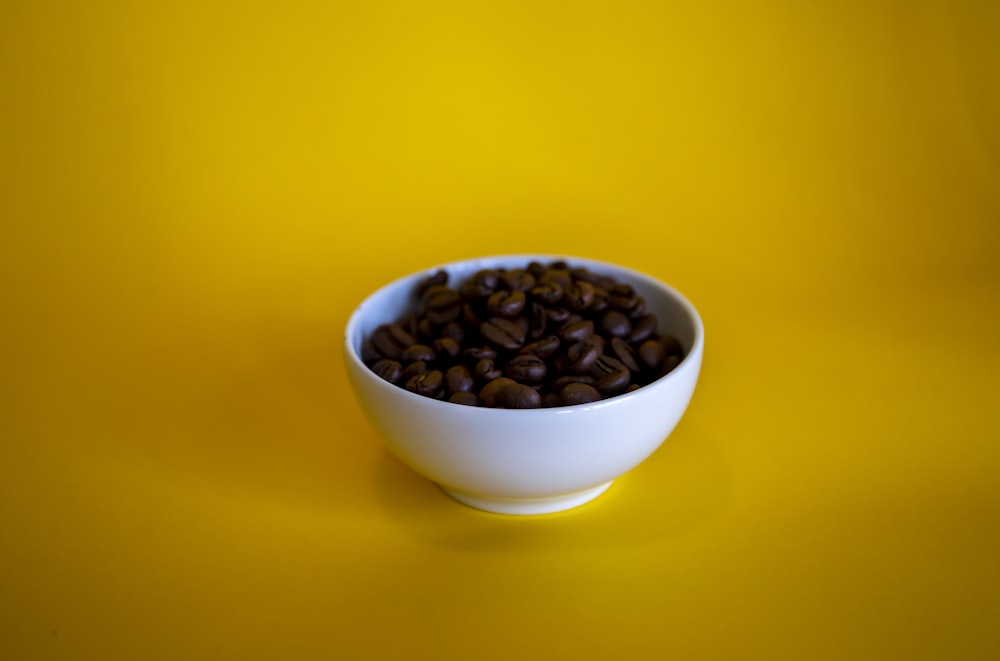 a bowl of coffee beans on a yellow background