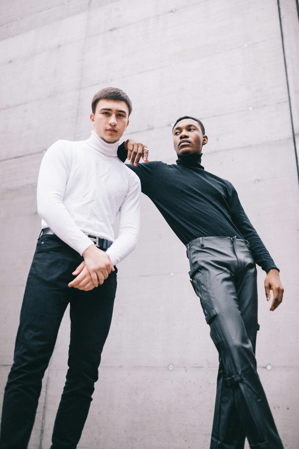 man in white sweater and gray pants standing beside man in black sweater