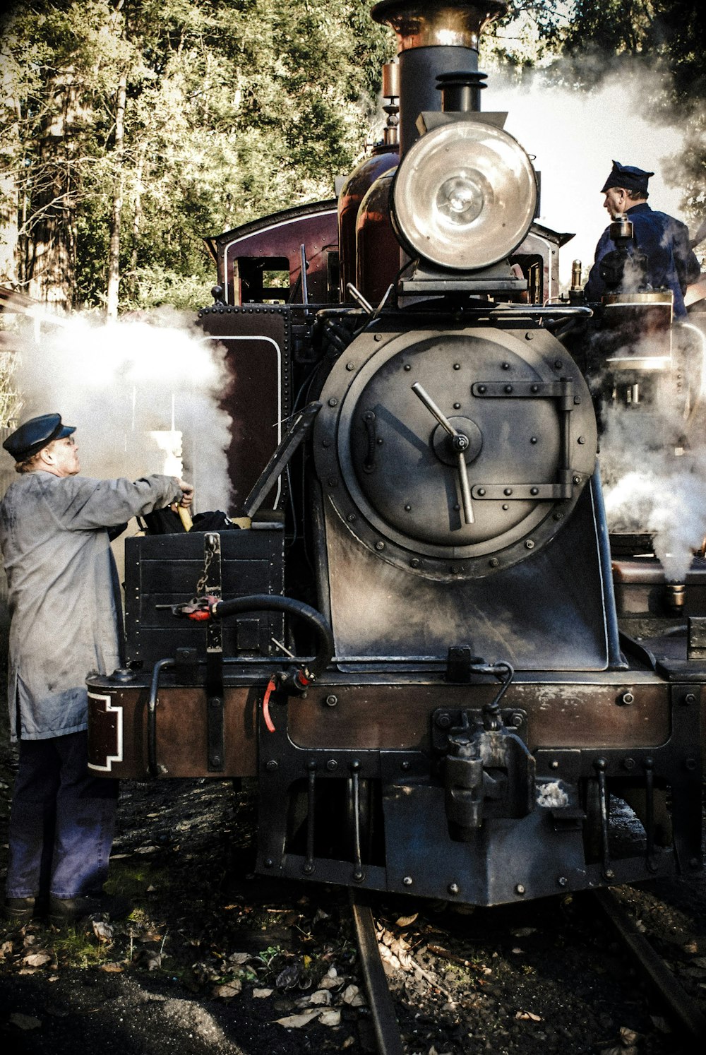 man in gray jacket standing near black and brown train