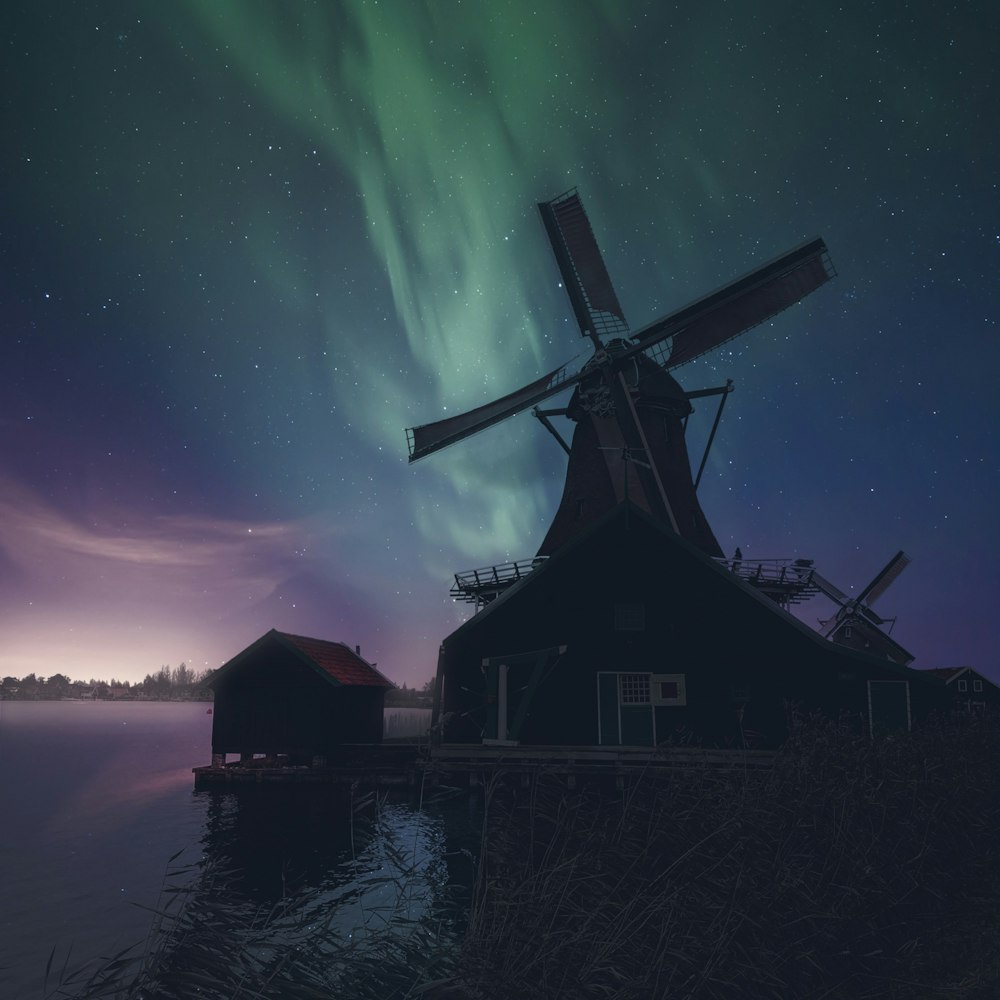 silhouette of house near body of water during night time