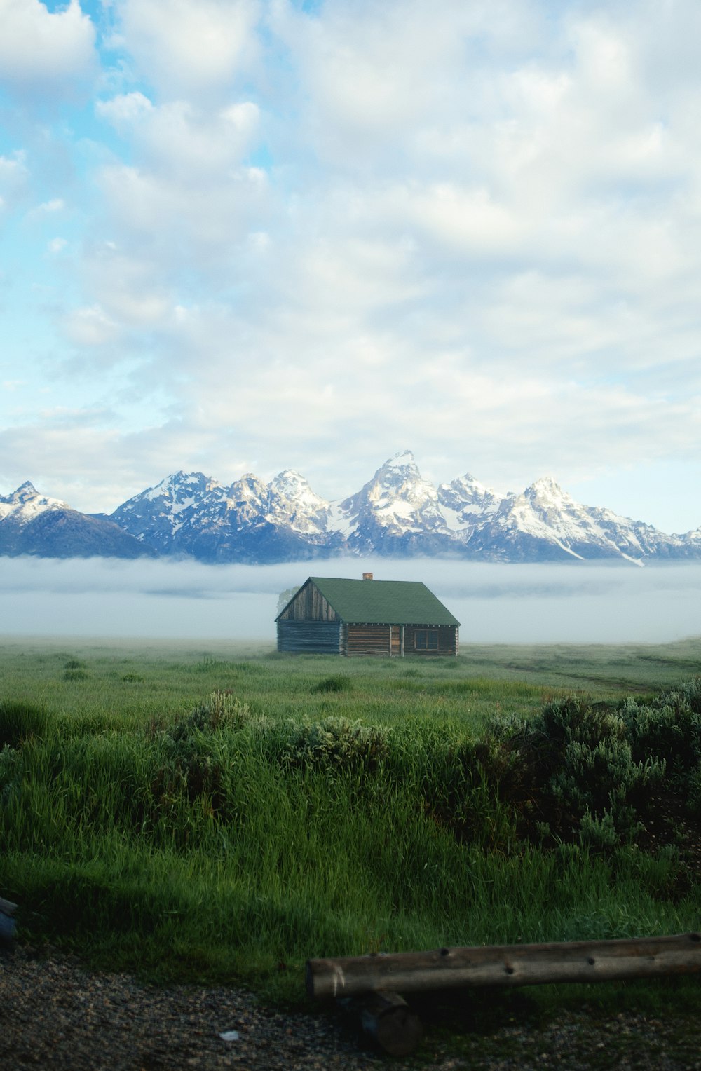 brown wooden house on green grass field near body of water during daytime