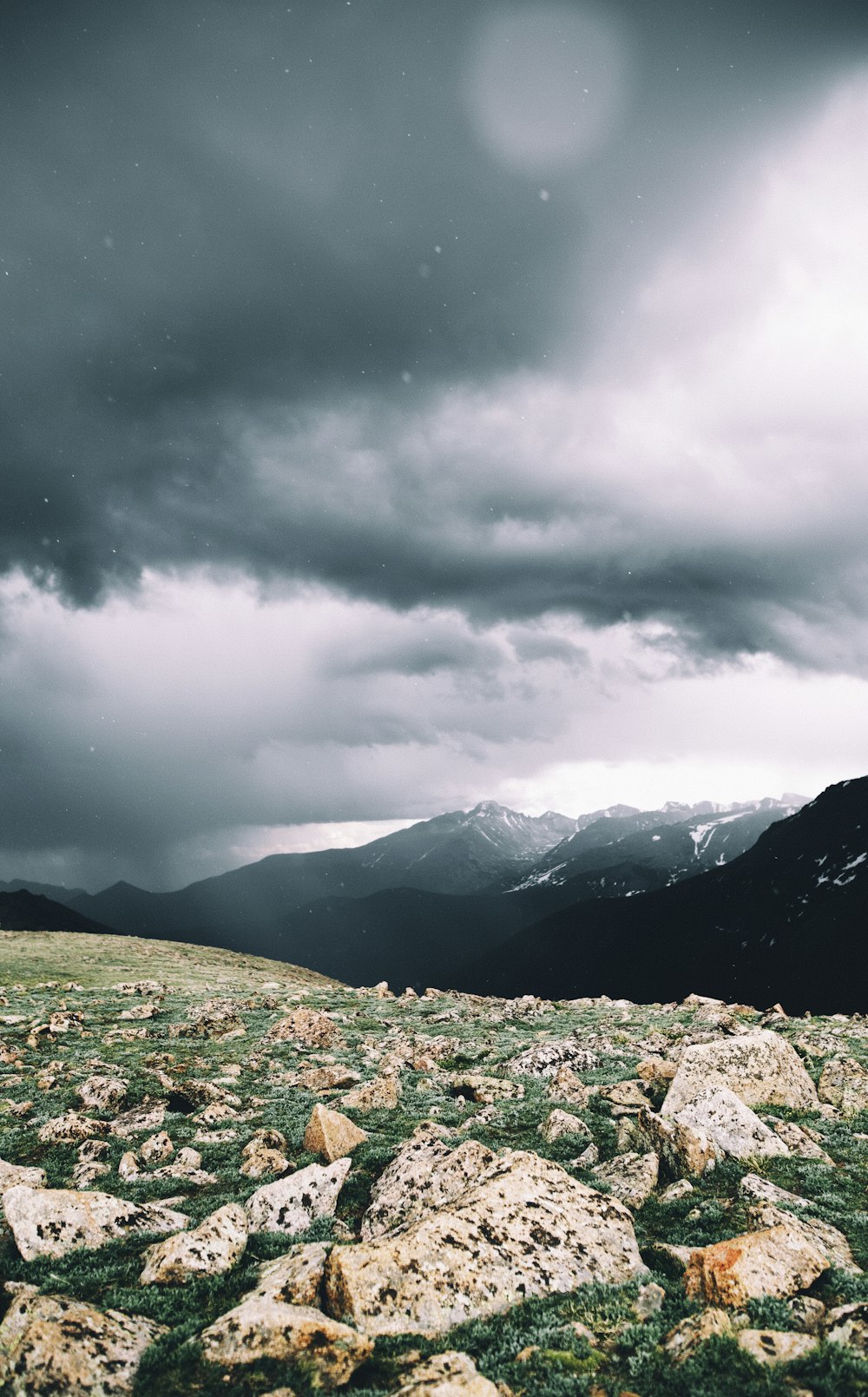 green grass field near mountains under cloudy sky during daytime