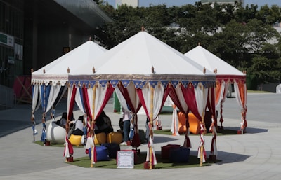 A cozy party setup with pastel red and white tents, tables, and chairs arranged outdoors.