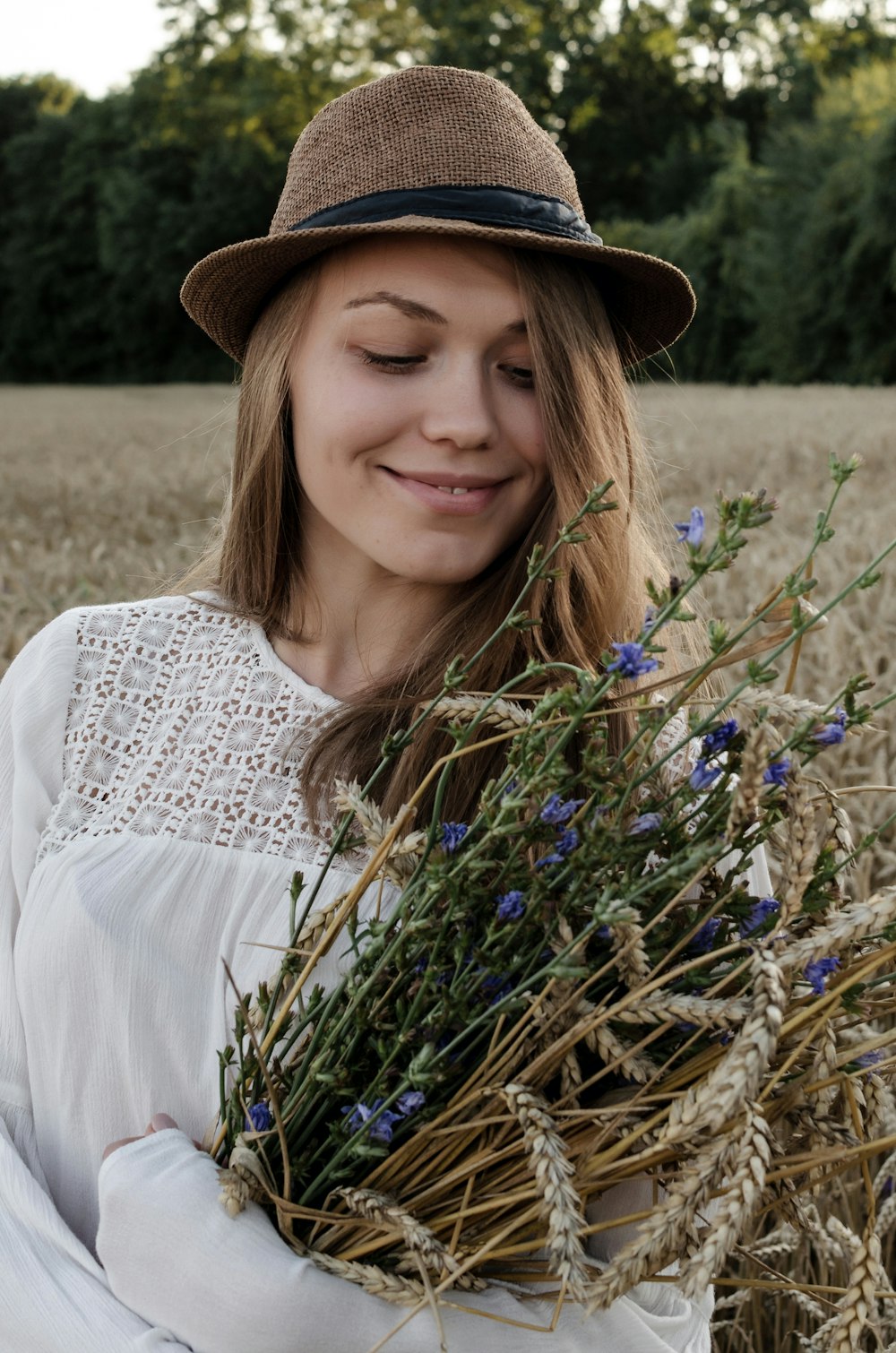 a woman in a hat holding a bunch of flowers