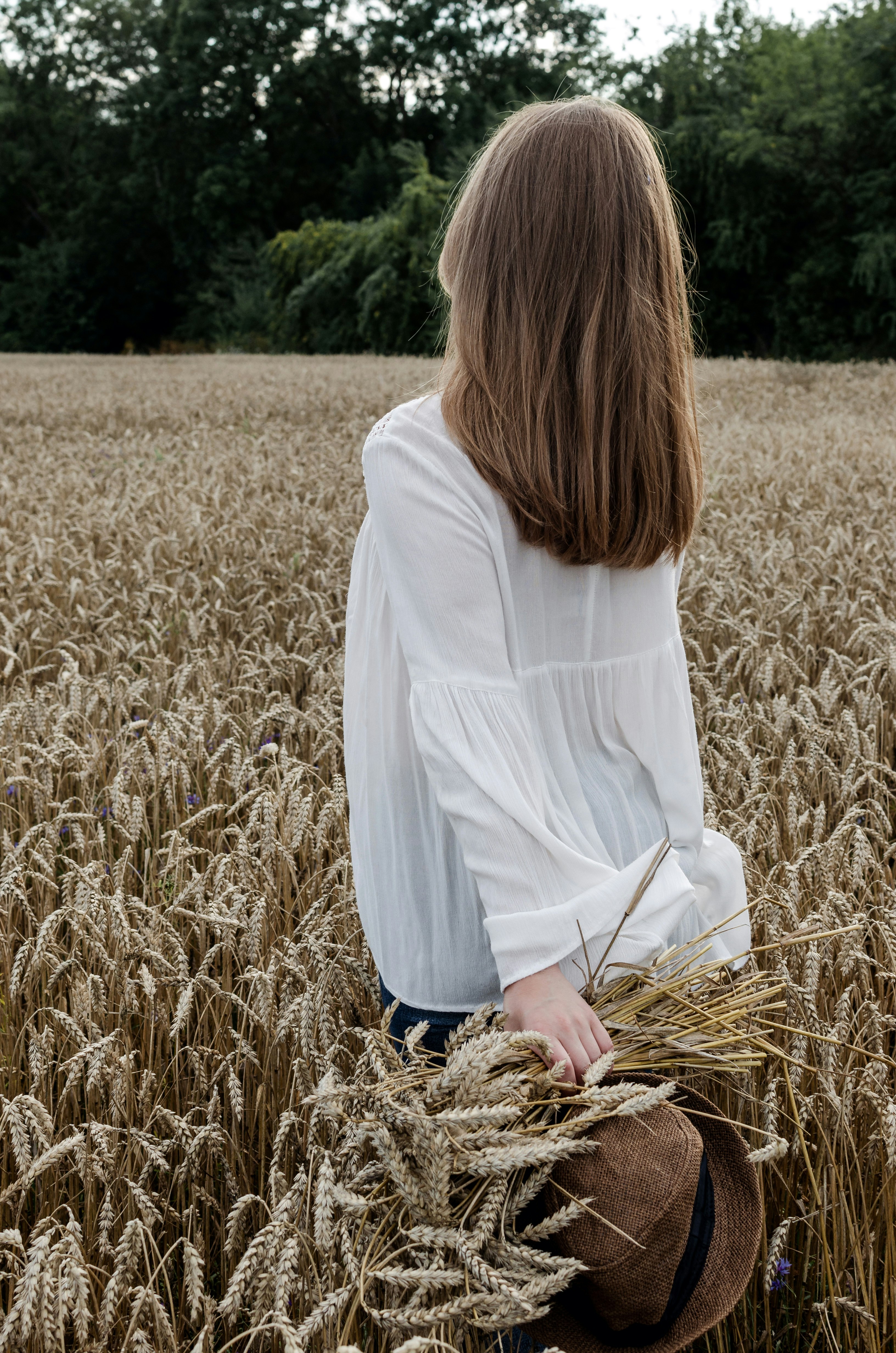 woman in white long sleeve shirt standing on brown grass field during daytime