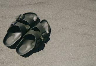 A pair of minimalist bamboo sandals placed beside green leaves, emphasizing the eco-friendly and natural materials.