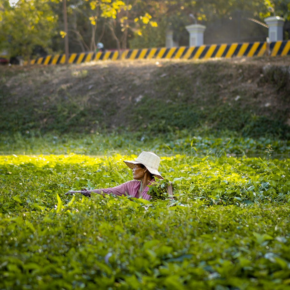 woman in blue sun hat and brown coat walking on green grass field during daytime