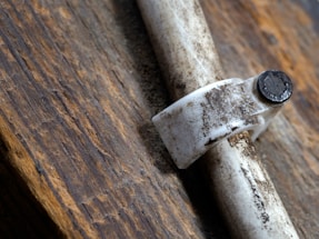A close-up of a hand applying butyl rubber pipe repair tape on a leaking pipe.