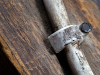 Close-up of hands tightening a pipe joint against a confederate grey wall background.