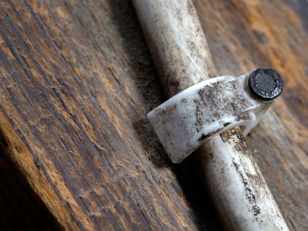 Close-up of hands tightening a pipe joint with an old-fashioned pipe wrench.