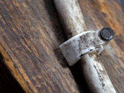 Close-up of hands tightening a pipe joint against a confederate grey wall background.