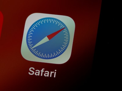 A close-up of an app icon displaying a compass with a red and blue needle, surrounded by a gray border. The app's name, 'Safari', is visible underneath in white text against a dark red background.