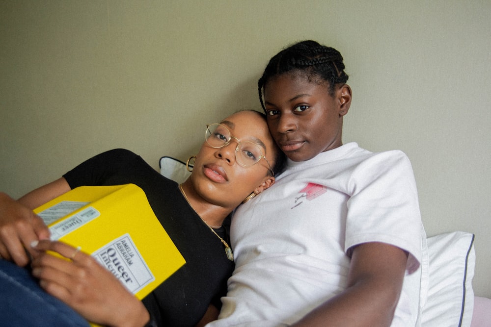 a couple of women laying next to each other on a bed