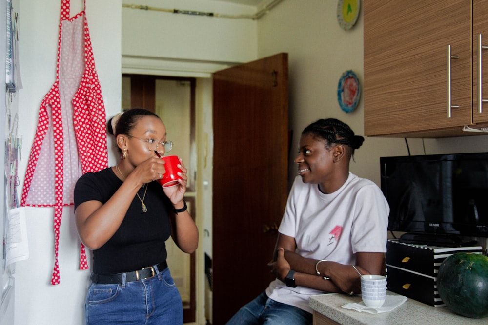 woman in black t-shirt drinking from red drinking glass