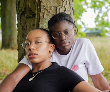 woman in black t-shirt wearing eyeglasses sitting with woman in white t-shirt wearing eyeglasses