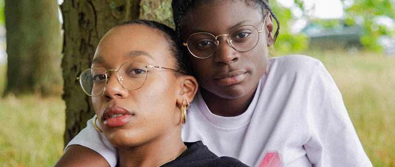 woman in black t-shirt wearing eyeglasses sitting with woman in white t-shirt wearing eyeglasses