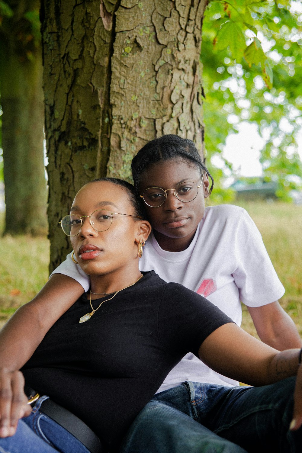 woman in black t-shirt wearing eyeglasses sitting with woman in white t-shirt wearing eyeglasses