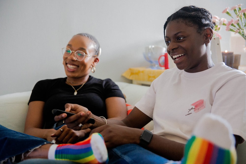 women sitting on white sofa watching television