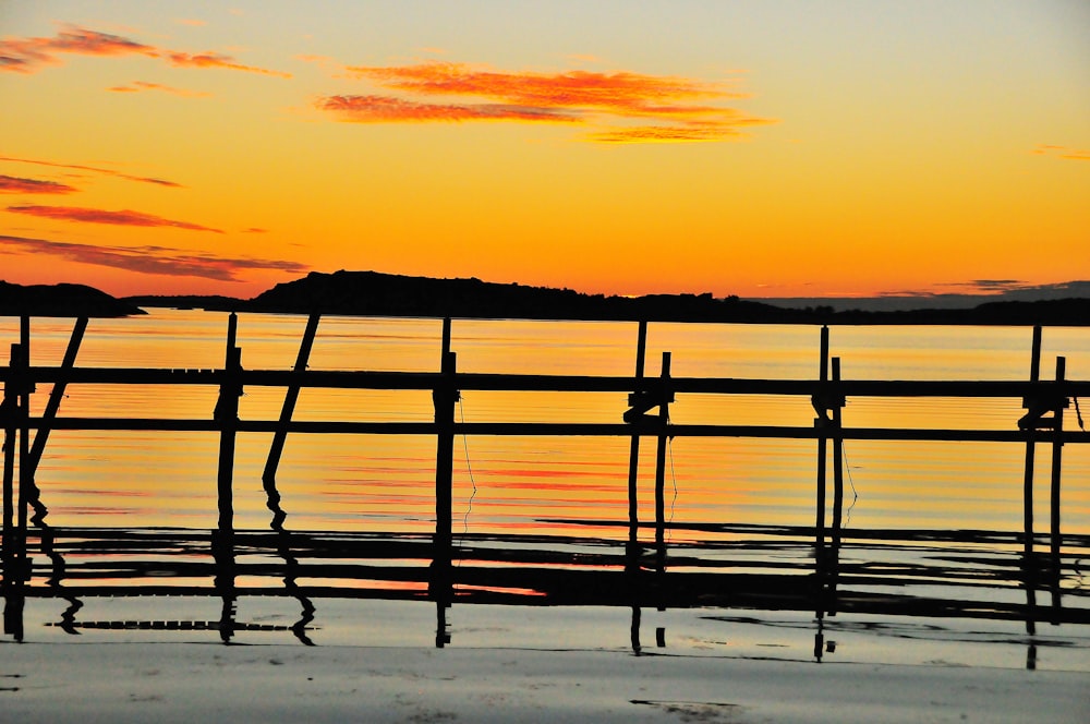 Silueta del muelle de madera en el mar durante la puesta del sol