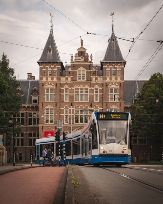 blue and white tram in front of brown concrete building during daytime in Tropenmuseum Netherlands