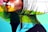 A vibrant street art mural featuring a stylized side profile of a face with bold graphic lines and vivid colors. The artwork combines brush strokes and geometric shapes with a palette of reds, greens, blues, and yellows, creating a dynamic and modern aesthetic.