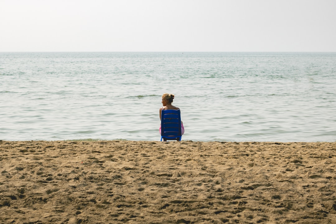 woman in blue dress standing on brown sand near body of water during daytime