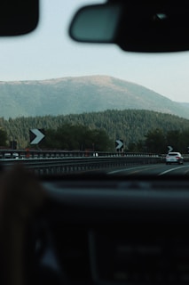 A scenic view of a winding road through the mountains, showcasing a car driving along the route.