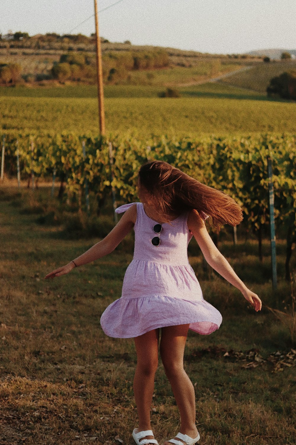 girl in white dress walking on green grass field during daytime