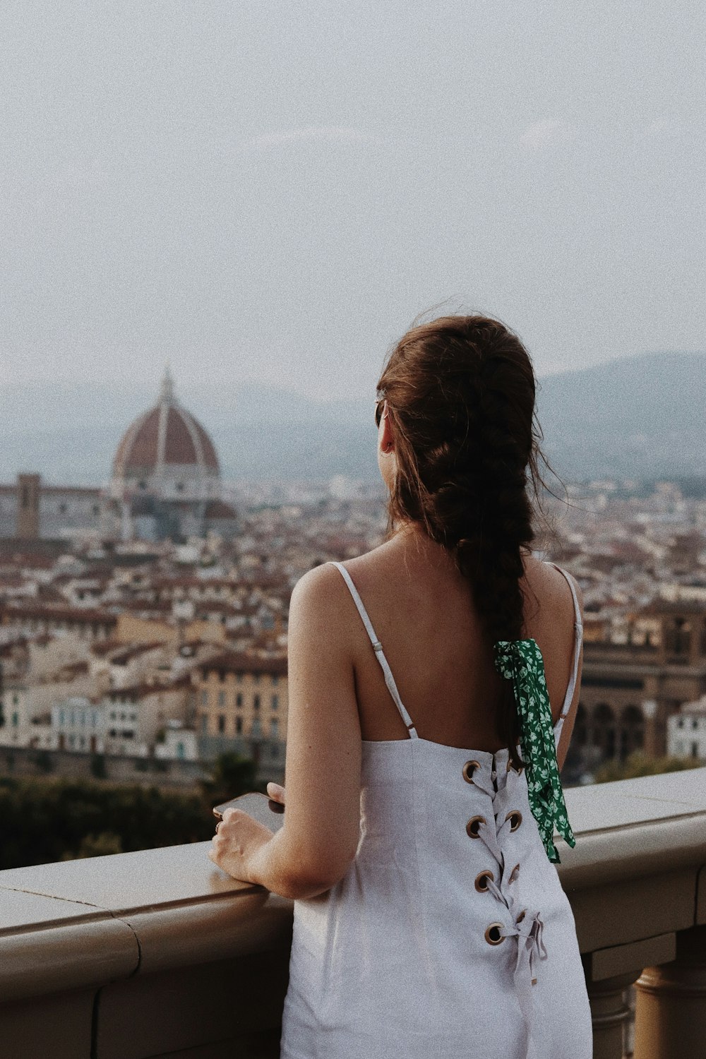 woman in white spaghetti strap top standing on balcony during daytime