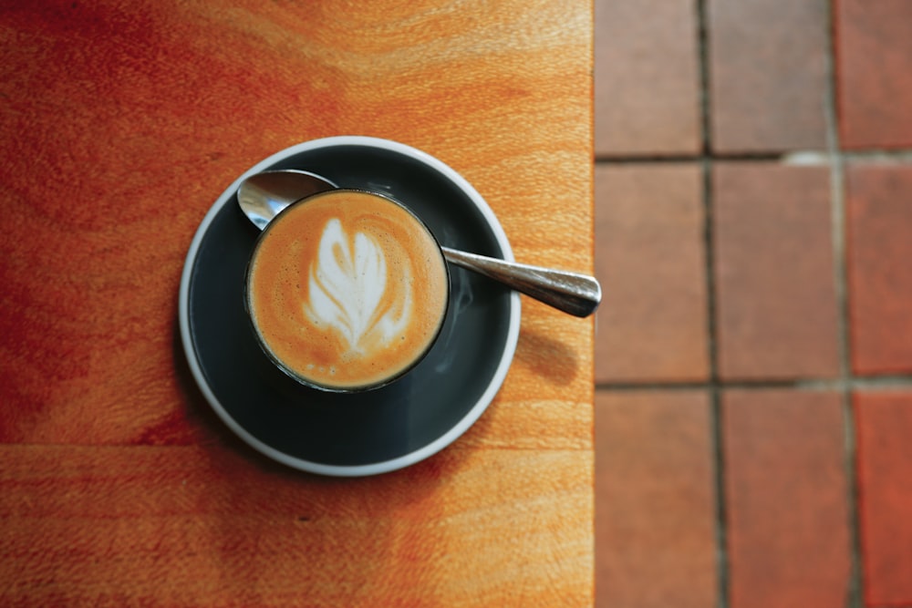 black ceramic mug with cappuccino on brown wooden table