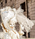 Handcrafted lace mask resting on a stone surface resembling pietra serena, with Ponte Vecchio softly blurred in the background.