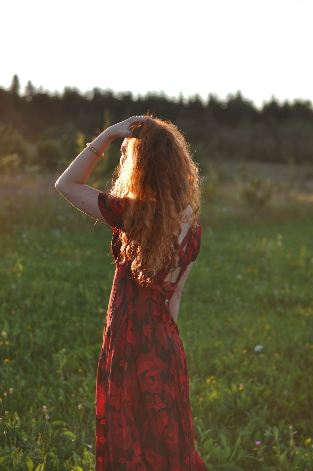 woman in red sleeveless dress standing on green grass field during daytime