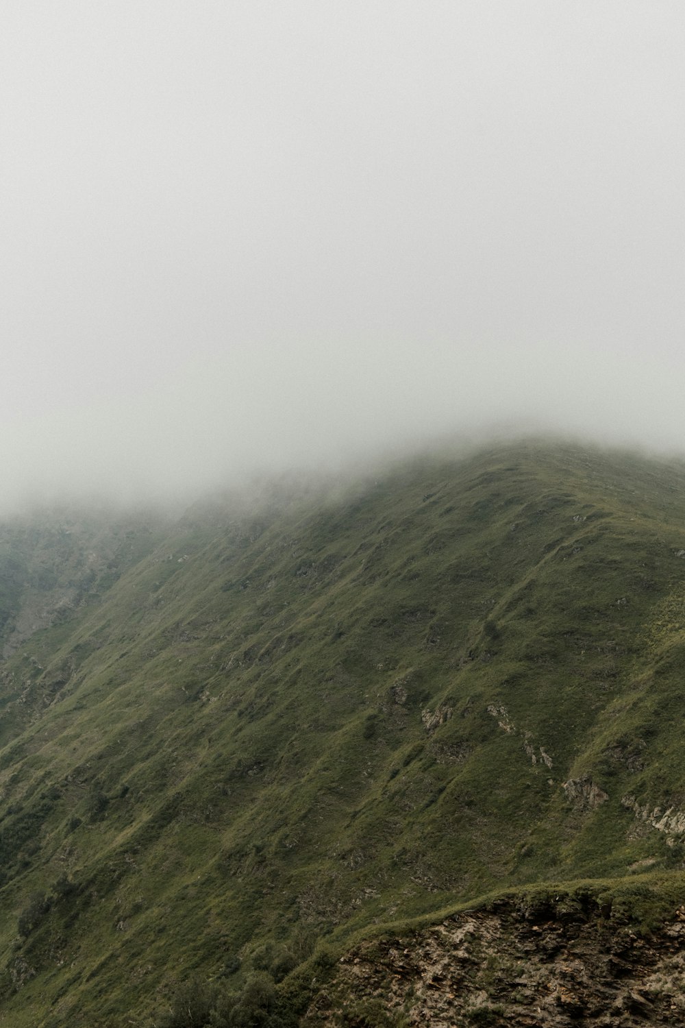 green grass covered mountain under white sky during daytime