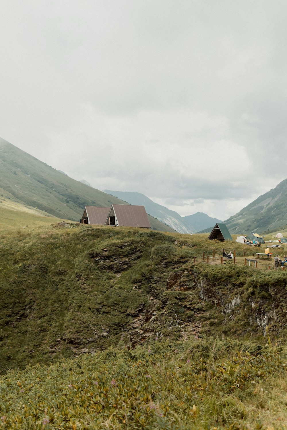 green grass field near mountain under white clouds during daytime