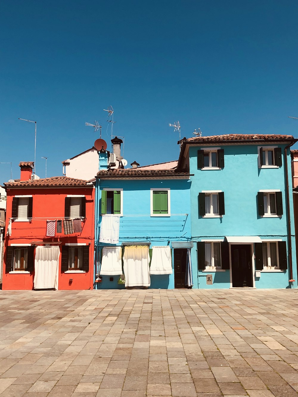 blau-weiße und rote Betonhäuser unter blauem Himmel tagsüber