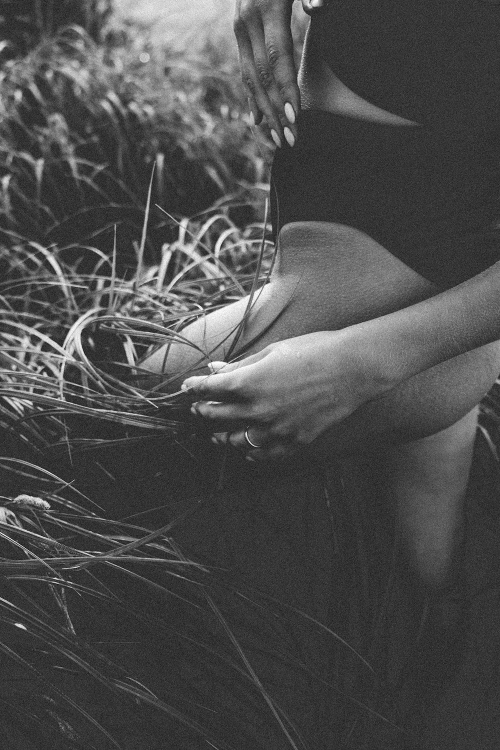 草の中に座っている女性の白黒写真