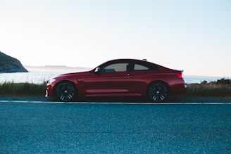 Shiny red sports car speeding along a coastal highway