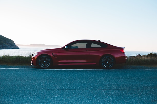 Shiny red sports car speeding along a coastal highway