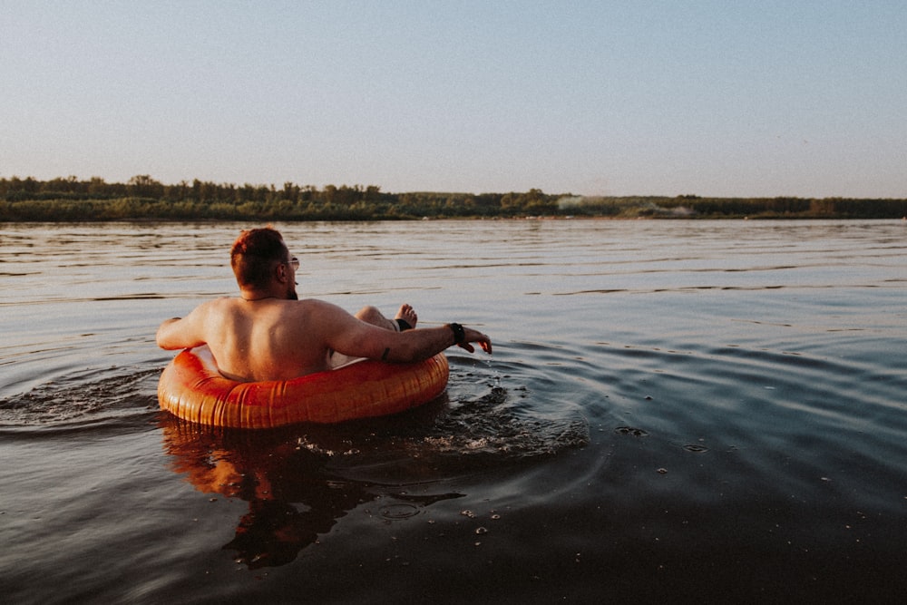 topless man in brown inflatable pool on water during daytime