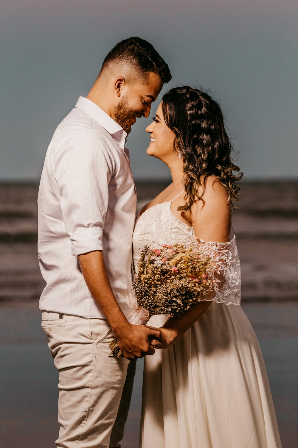 man in white dress shirt kissing woman in white floral dress