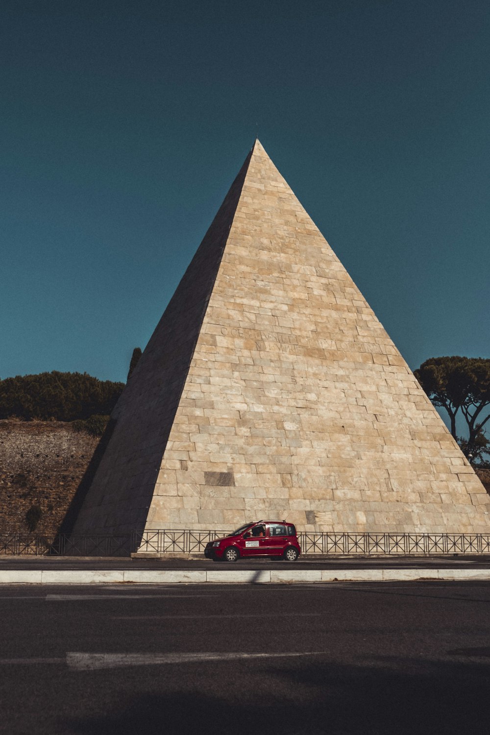 red coupe parked beside brown concrete building during daytime