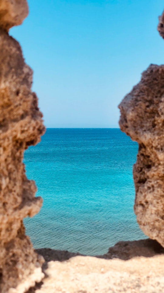 brown rock formation near blue sea under blue sky during daytime in Rhodes Greece