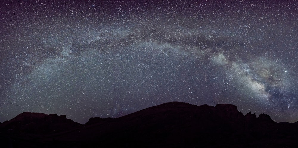 silhouette of mountain under starry night