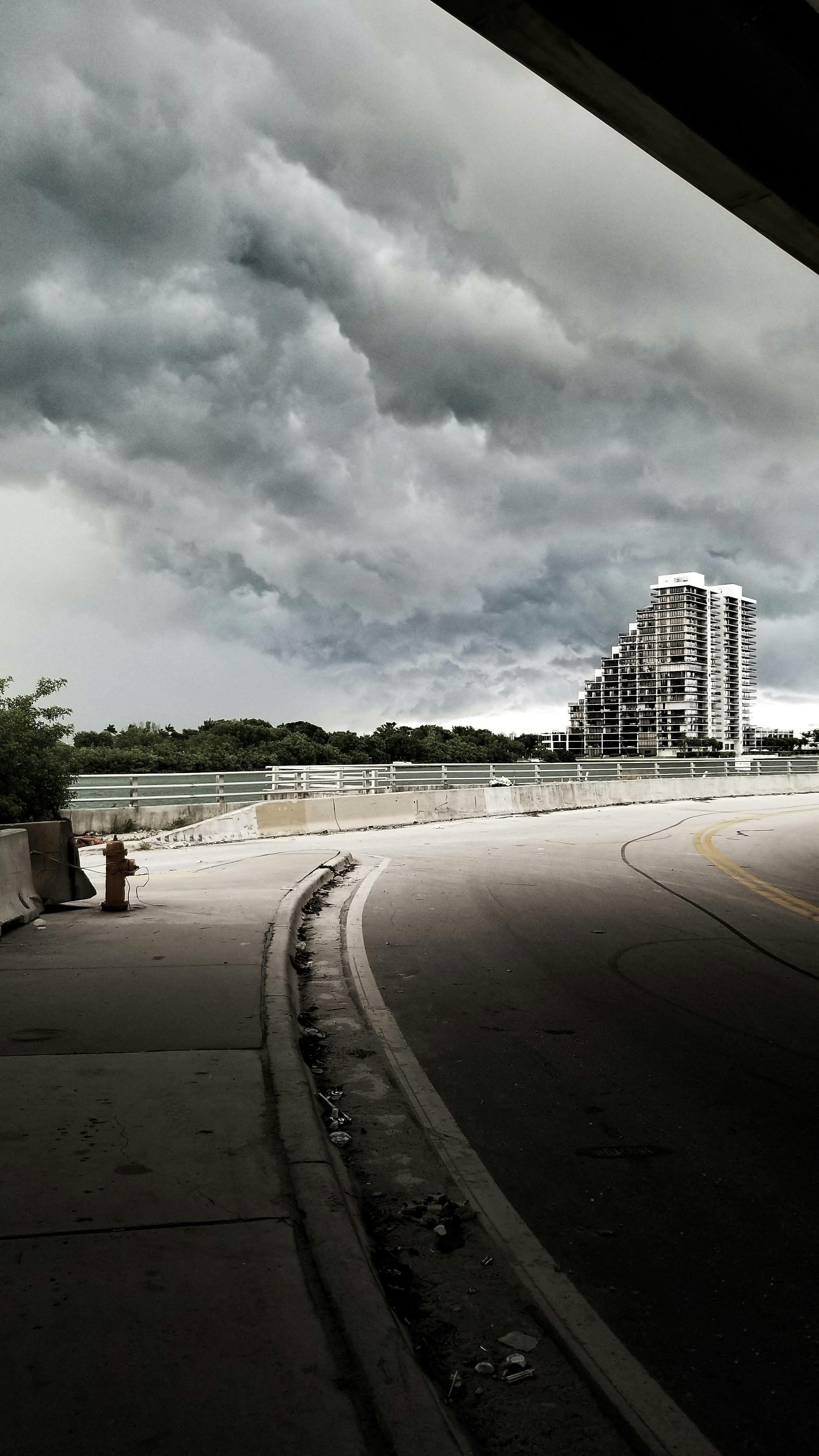 gray concrete road near city buildings under white clouds during daytime