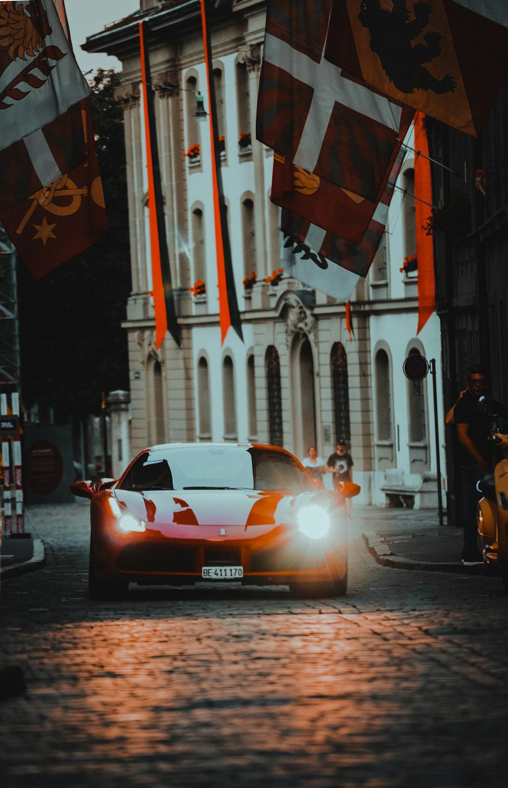 orange porsche 911 parked beside white and red concrete building during nighttime