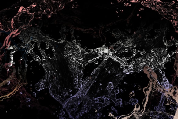 Chaotic splashes and streams of water are captured mid-movement against a dark background, creating an abstract and dynamic visual effect. The water appears in various transparent shapes and forms, giving an impression of fluidity and motion.