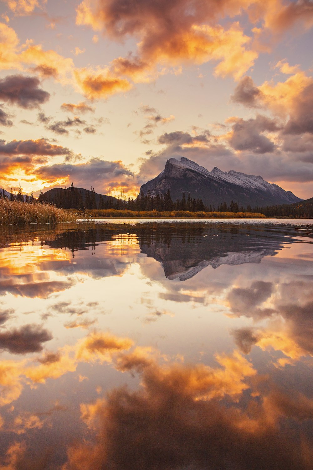 body of water near mountain under cloudy sky during daytime