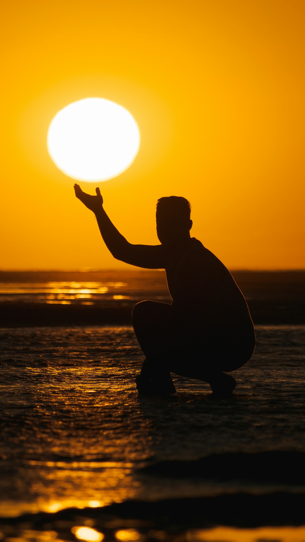 silhouette of man sitting on rock during sunset