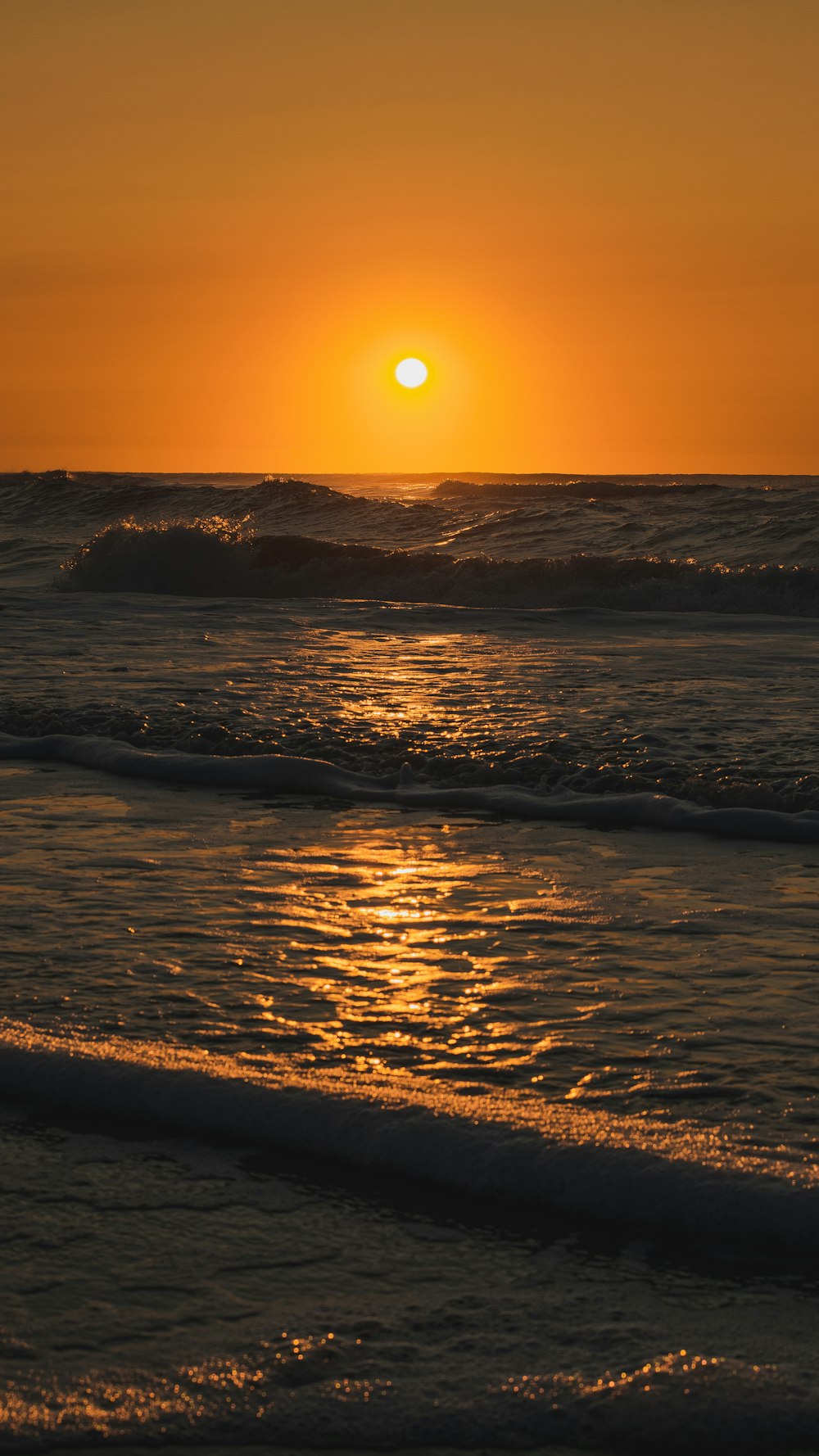 ocean waves crashing on shore during sunset