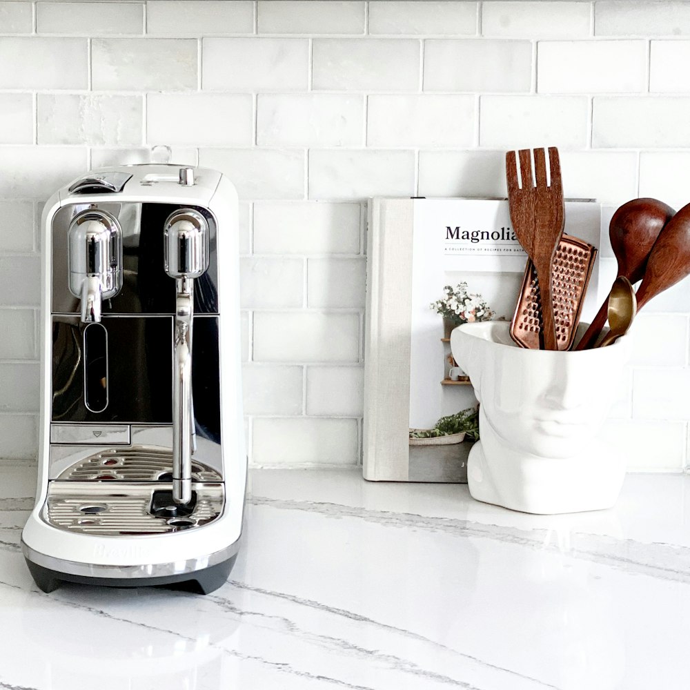 white and silver coffee maker beside white ceramic mug